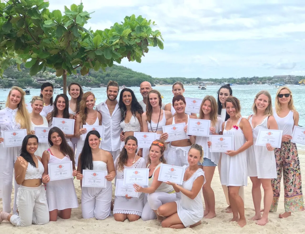 A graduating group holding their certificates on the beach in Nusa Lembongan